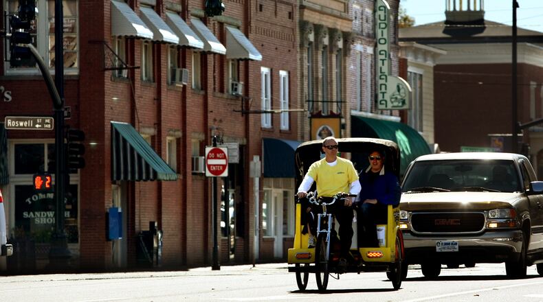 101113 Marietta; Brian Buckalew, owner of Marietta Pedicabs, gives a ride to customer R.J. Chapple, of Suwanee, right, and his two daughters Kristina, 11, and Kathlryn, 8, down East Park Square in historic Marietta Square Saturday morning in Marietta, Ga., Nov. 13, 2010. Buckalew, owns Marietta Pedicabs with his wife Cassandra, have been operating in downtown Marietta for around 7 months. Marietta Pedicabs serves historic Marietta Square and neighboring areas with fares as low as $1. Atlanta is developing a permitting system for human-pulled carts to ferry folks around. Several cities around the state have pedi-carts, including Savannah and closer to home in Decatur and in Marietta.