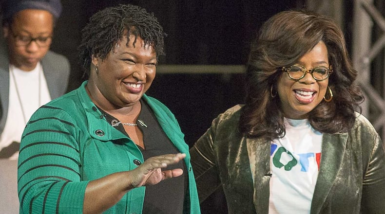 Oprah Winfrey, right, and Georgia gubernatorial candidate Stacey Abrams greet a crowd gathered for a town hall conversation Thursday at the Cobb Civic Center’s Jennie T. Anderson Theatre in Marietta. (ALYSSA POINTER/ALYSSA.POINTER@AJC.COM)