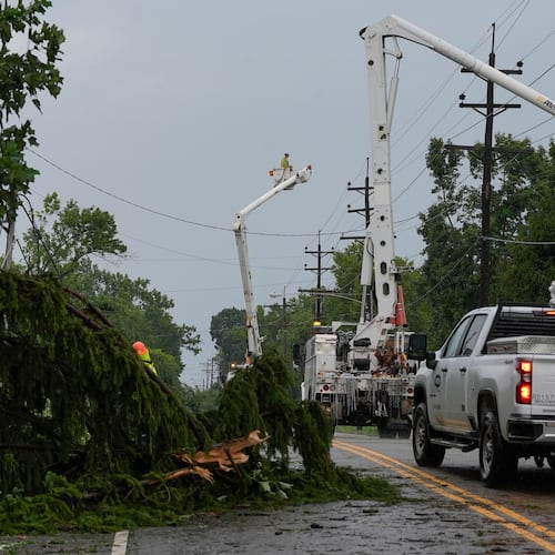 Crews work along Race Road among trees and power lines downed by severe storms on Tuesday, to restore power in Cincinnati on Wednesday, Aug. 12, 2026. (AP Photo/Carolyn Kaster)