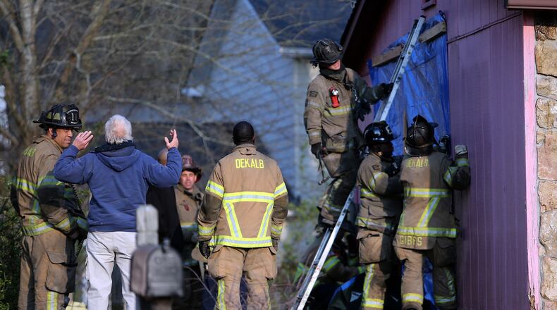 March 25, 2014 DeKalb County: DeKalb County firefighters work to secure a tarp to the side of a house Tuesday afternoon March 25, 2014 after a man had a heart attack and lost control of his truck. Neighbors said the man's 13-year-old daughter was in the passenger seat and grabbed the steering wheel to try to regain control before it hit the house. BEN GRAY / BGRAY@AJC.COM