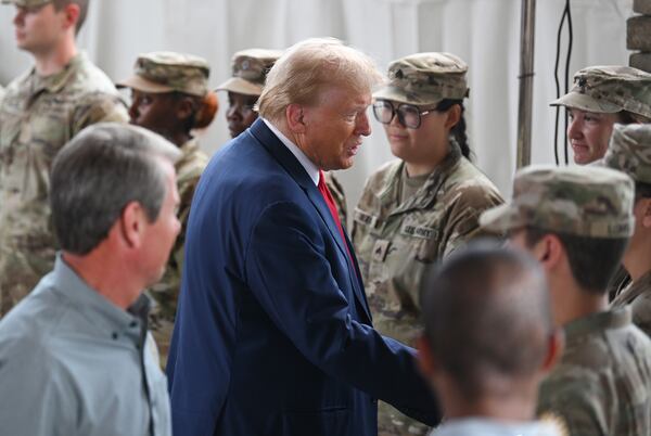 Then-former President Donald Trump and Gov. Brian Kemp, seen here shaking hands with members of the Army National Guard in Evans in 2024. (Hyosub Shin/AJC)