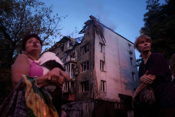 Local residents stand outside of their house which was heavily damaged by a Russian strike in Kyiv, Ukraine, on Thursday, July 10, 2025. (AP Photo/Evgeniy Maloletka)