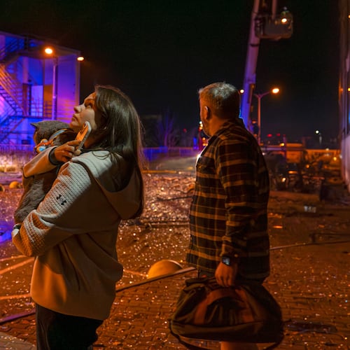 People watch as emergency services personnel work to extinguish a fire following a Russian attack in Kyiv, Ukraine, Tuesday, Nov. 25, 2025. (AP Photo/Dan Bashakov)