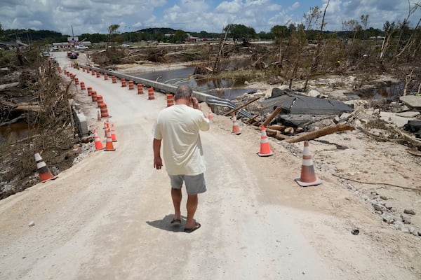 Resident Paul Snyder walks down the road to check out the condition of the bridge along the Guadalupe River after flooding in Kerrville, Texas on Wednesday , July 9, 2025. (AP Photo/Gerald Herbert)