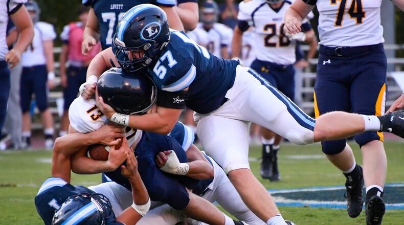 High school football: Lovett's Luke Wahl (57) and Collin Goldberg (1) bring down Marist quarterback Connor Cigelske (13) in the first quarter of a recent game at Lovett. (John Amis/Special)