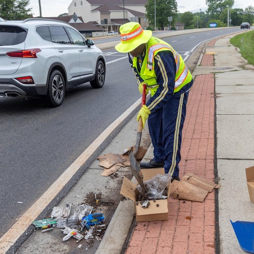 Anthony "Spark Plug" Thomas cleans up litter & debris at the Highway 92 traffic circle at Antioch & Lockwood roads in Fayetteville in 2024. (Phil Skinner for the AJC)