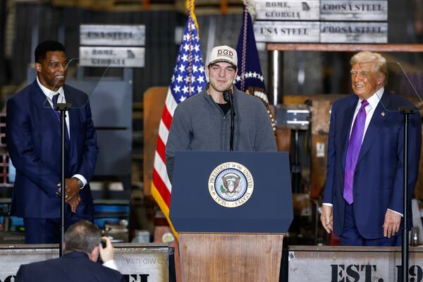 UGA quarterback Gunner Stockton appears alongside U.S. Ambassador to the Bahamas and former UGA football star Herschel Walker (left) and President Donald Trump (right) at Trump’s rally Thursday, February 19, 2026. (Arvin Temkar/AJC)