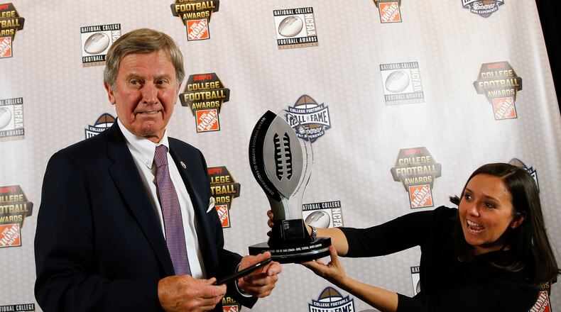 Former coach Steve Spurrier gets help taking a photo of the trophy after being awarded the Contributions to College Football Award on Thursday. (AP photo/John Bazemore)