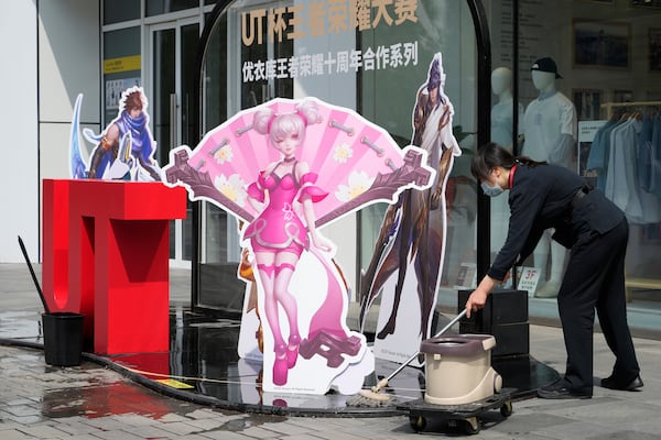 A worker wipes the ground near a promotion display at a mall in Beijing, Wednesday, May 7, 2025. (AP Photo/Ng Han Guan)