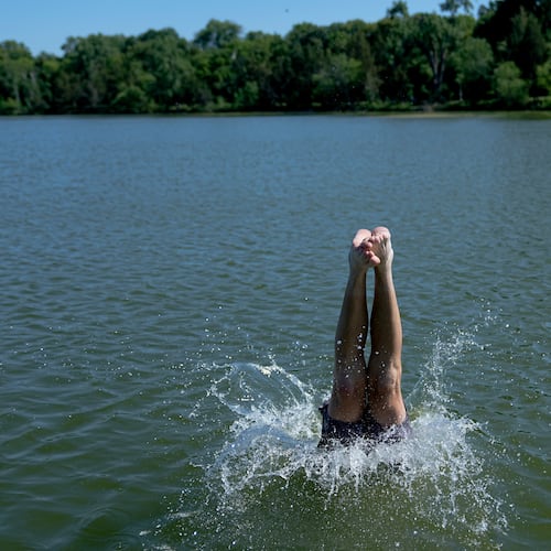 A swimmer dives into Cedar Lake during an extreme heat warning Monday, July 13, 2026, in Minneapolis. (AP Photo/Ellen Schmidt)