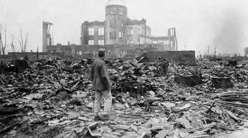 This Sept. 8, 1945, picture shows an Allied correspondent standing in the rubble in front of the shell of a building that once was a movie theater in Hiroshima, Japan, a month after the first atomic bomb ever used in warfare was dropped by the U.S. (AP Photo/Stanley Troutman)