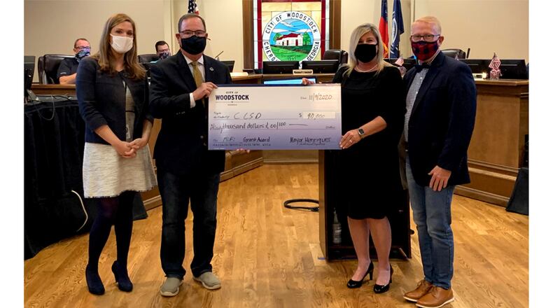 Woodstock Mayor Henriques presents a $90,000 check to Cherokee County schools Superintendent Brian Hightower at the City Council meeting Monday, Nov. 9. The grant will fund mobile WiFi hotspot devices.