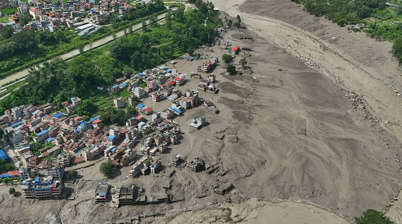 Damaged houses stand precariously near the swollen, debris-choked banks of the Trishuli River after flash floods in Nepal's Nuwakot district on Wednesday, Aug. 26, 2026. (AP Photo/Niranjan Shrestha)
