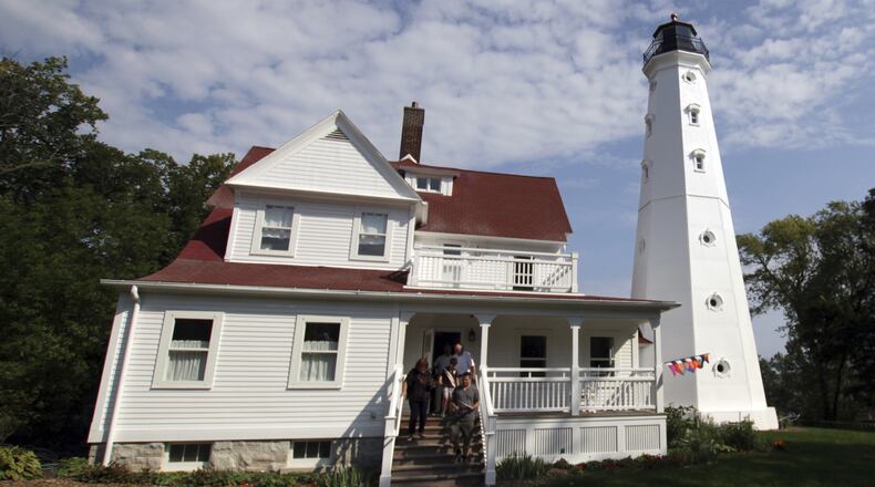 In this photo taken Sunday, Sept. 25, 2016, a family walks out of the North Point Lighthouse in Milwaukee after a tour. About 120 lighthouses no longer critical to the U.S. Coast Guard in 22 states and Puerto Rico have been acquired at no cost by government entities and nonprofits, or sold to private individuals eager to preserve the landmarks and tap into their tourism potential since they became available under the National Historic Lighthouse Preservation Act of 2000. (AP Photo/Carrie Antlfinger)
