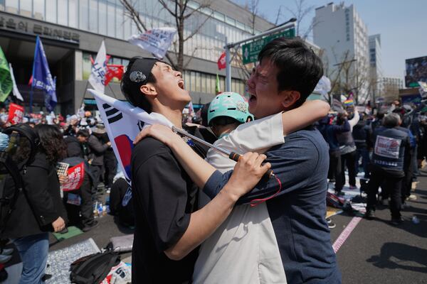 People react after hearing the news that President Yoon Suk Yeol was removed from office, in Seoul, South Korea, Friday, April 4, 2025. (AP Photo/Lee Jin-man)