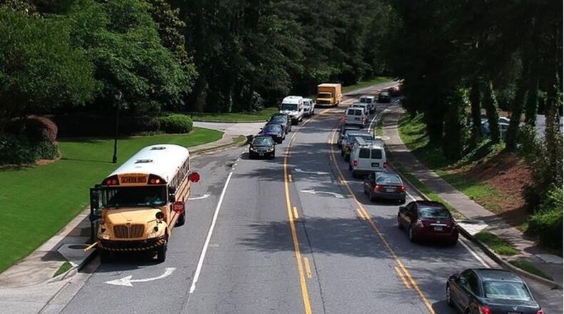 Fulton County Schools bus stops on Powers Ferry Road in Sandy Springs on Wednesday, May 23, 2018. A phrase added to a 15-page bill approved late in the Georgia legislative session last year has caused panic among officials responsible for getting children to and from school safely. HYOSUB SHIN / HSHIN@AJC.COM