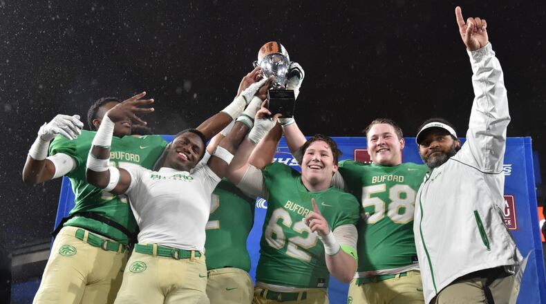 Buford players and coach Bryant Appling hold their championship trophy after the GHSA AAAAA state championship game at Georgia State Stadium on Friday, December 13, 2019. Buford won 17-14 over Warner Robins in overtime. (Hyosub Shin / Hyosub.Shin@ajc.com)