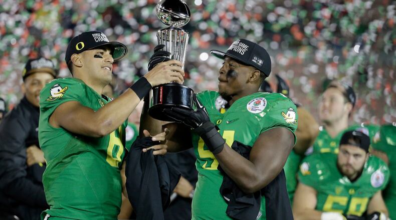 PASADENA, CA - JANUARY 01: Quarterback Marcus Mariota #8 of the Oregon Ducks hands the Leishman Trophy to linebacker Tony Washington #91 after defeating the Florida State Seminoles 59-20 in the College Football Playoff Semifinal at the Rose Bowl Game presented by Northwestern Mutual at the Rose Bowl on January 1, 2015 in Pasadena, California. (Photo by Jeff Gross/Getty Images) Marcus Mariota hands trophy to Oregon teammate Tony Washington after the Ducks beat FSU in Rose Bowl. (Jeff Gross/Getty Images)