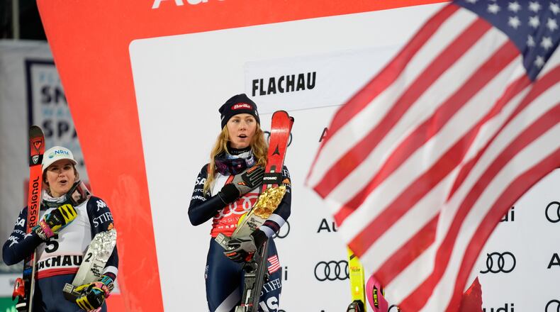 United States' Mikaela Shiffrin, center, winner of an alpine ski, women's World Cup slalom, listens to the national anthem with second placed United States' Paula Moltzan, in Flachau, Austria, Tuesday, Jan. 13, 2026. (AP Photo/Giovanni Auletta)