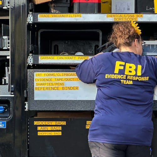 An FBI agent stands by an Evidence Response Team truck outside a home in a Dearborn, Mich., neighborhood on Friday, Oct. 31, 2025. (AP Photo/Mike Householder)