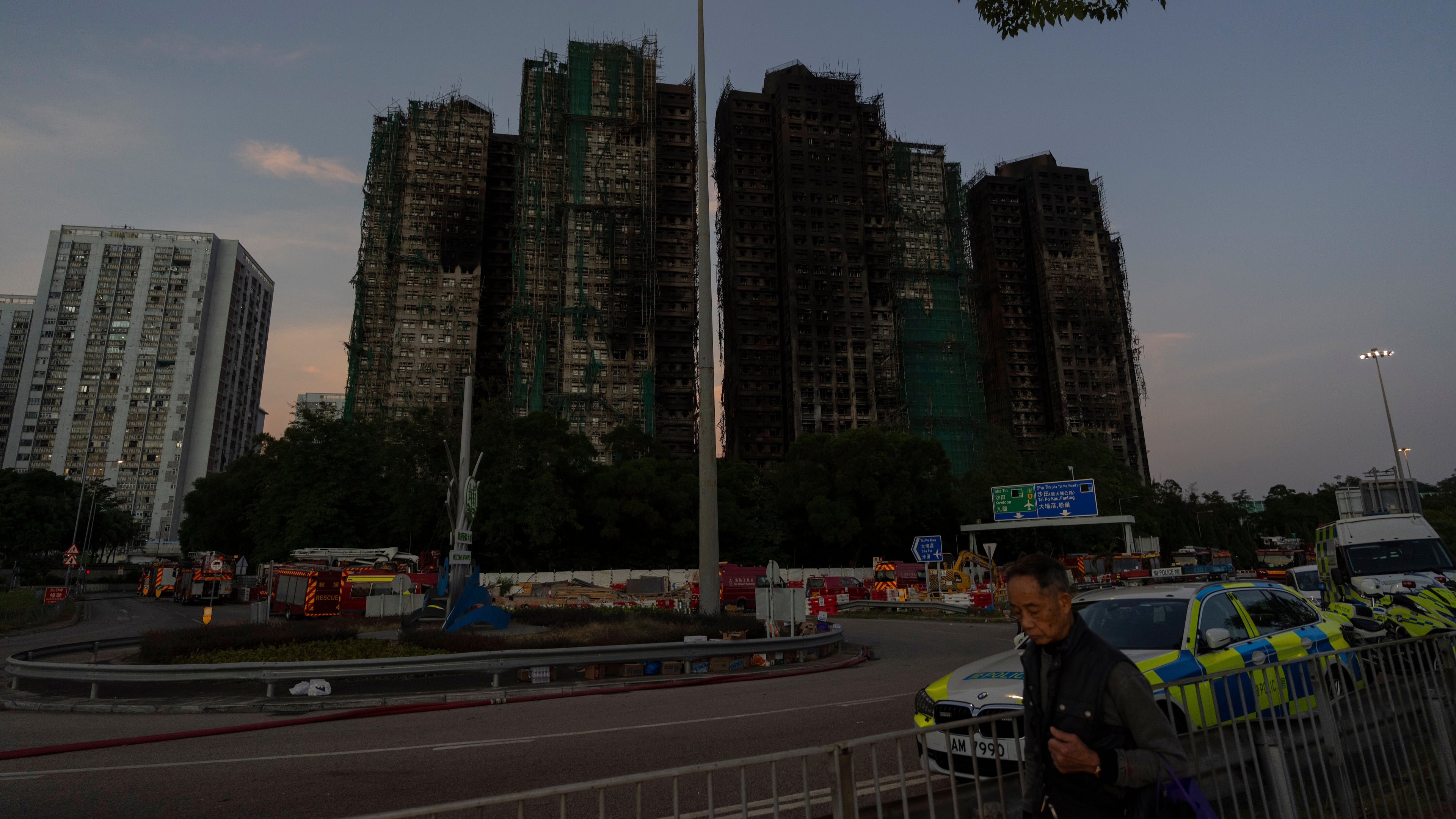 A man walks past charred buildings burnt after a deadly fire that started Wednesday at Wang Fuk Court, a residential estate in the Tai Po district of Hong Kong's New Territories, Friday, Nov. 28, 2025. (AP Photo/Ng Han Guan)