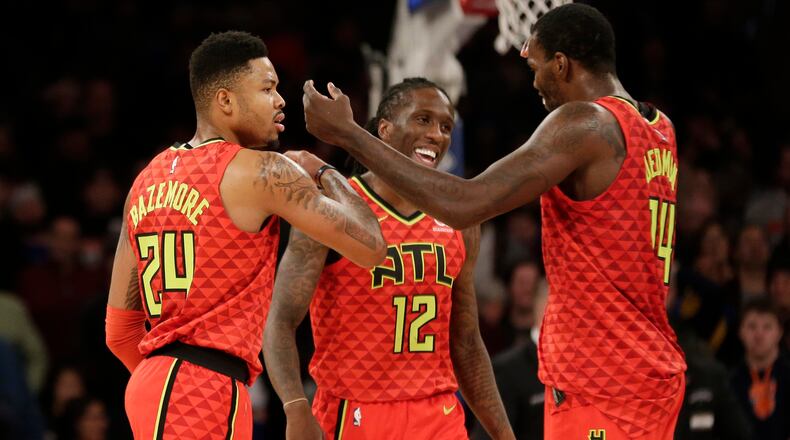 Atlanta Hawks' Kent Bazemore, left, celebrates his three-point basket with Taurean Prince, center, and Dewayne Dedmon during the last seconds of the second half of an NBA basketball game against the New York Knicks, Sunday, Feb. 4, 2018, in New York. (AP Photo/Seth Wenig)