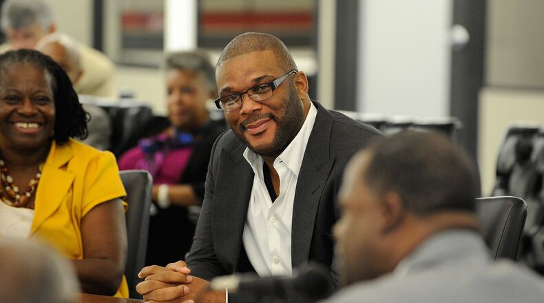 Tyler Perry, center, attends a hearing where Mayor Kasim Reed, right, announced an agreement on redevelopment plans for 330 acres of the former Army base at Fort McPherson, centered around the filmmaker's vision for a movie studio on Aug. 8 in Atlanta.