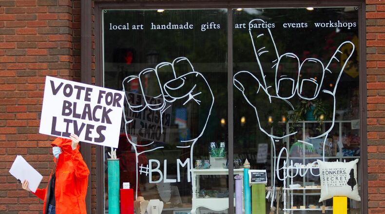 The Avondale Alliance for Racial Justice protesters hold up signs as cars drive by in Avondale Estates's downtown strip Saturday, August 29, 2020. STEVE SCHAEFER FOR THE ATLANTA JOURNAL-CONSTITUTION