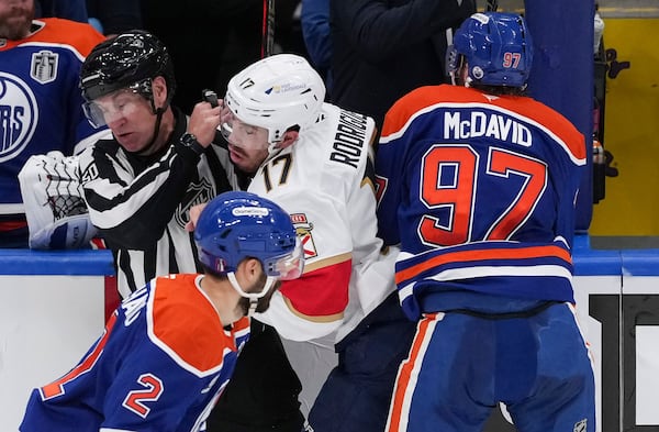 Edmonton Oilers' Connor McDavid (97) checks Florida Panthers' Evan Rodrigues (17) into linesman Scott Cherrey during the second period in Game 1 of the NHL hockey Stanley Cup final series in Edmonton, Alberta, Wednesday, June 4, 2025. (Darryl Dyck/The Canadian Press via AP)