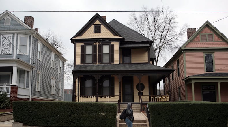 A passerby walks past the boyhood home (center) of the Rev. Dr. Martin Luther King Jr. Officials announced this week that renovations to the first floor of the 122-year-old home have been completed in time to re-open next Monday. The upper floor is still being refurbished and will remain closed to the public. JESSICA MCGOWAN / jmcgowan@ajc.com