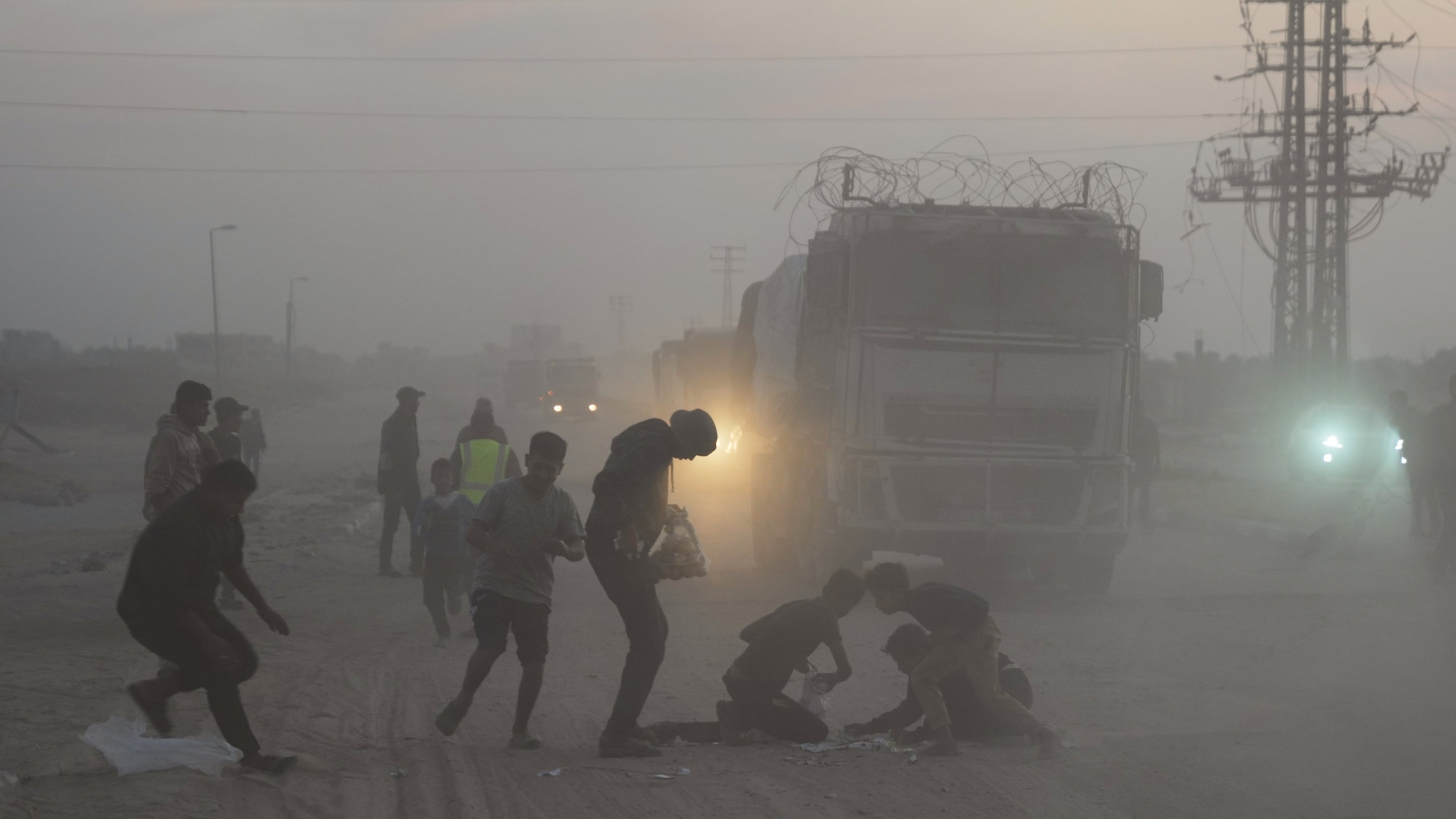 Palestinians rush toward trucks carrying aid from the World Food Programme (WFP) as they drive through Deir al-Balah in central Gaza, Saturday, Nov. 8, 2025. (AP Photo/Abdel Kareem Hana)