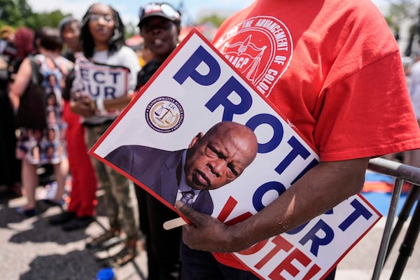 A protester holds a sign of the late Georgia Congressman John Lewis during a voting rally May 16, 2026, in Montgomery, Ala. (Mike Stewart/AP)