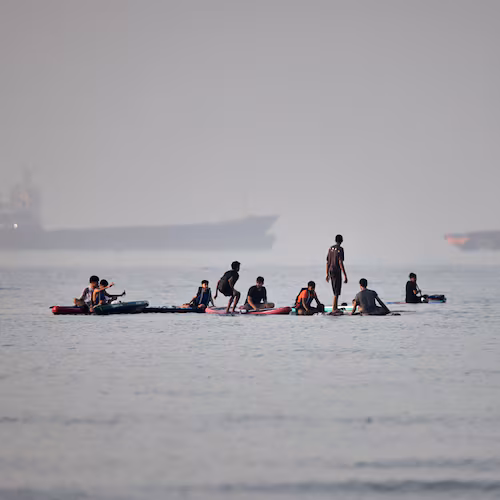 People gather on paddleboards in shallow water as cargo and service vessels are anchored in the Strait of Hormuz off Bandar Abbas, Iran, Monday, June 1, 2026. (Amirhosein Khorgooi/ISNA via AP)