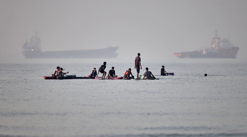 People gather on paddleboards in shallow water as cargo and service vessels are anchored in the Strait of Hormuz off Bandar Abbas, Iran, Monday, June 1, 2026. (Amirhosein Khorgooi/ISNA via AP)