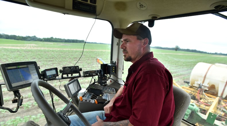 Todd Whitfield monitors the application of liquid nitrogen to a cotton field owned by Chuck and Matt Coley in Vienna on June 10, 2015. Whitfield has a host of electronics to monitor, but he doesn't have to actually steer the tractor. The auto steer tractor is able to prevent the overlapping application of chemicals.