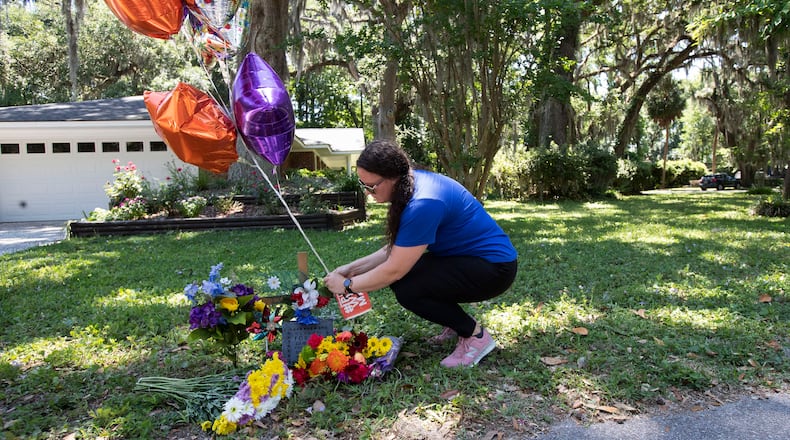 Erica Smith, of Brunswick, Ga., leaves a small paper sign on a memorial at the spot where an unarmed black man was shot and killed Friday, May 8, 2020, in Brunswick Ga. Two men have been charged with murder in the February shooting death of Ahmaud Arbery, whom they had pursued in a truck after spotting him running in their neighborhood. (AP Photo/John Bazemore)