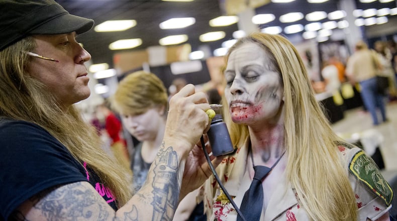 Shane Morton (left) spray-paints on Jenny Loaiza’s face as he turns her into a zombie during Walker Stalker Con at the Atlanta Convention Center at AmericasMart last November. CONTRIBUTED BY JONATHAN PHILLIPS / SPECIAL