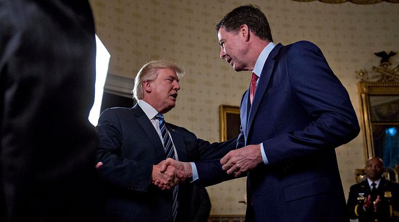 WASHINGTON, DC - JANUARY 22: U.S. President Donald Trump (C) shakes hands with James Comey, director of the Federal Bureau of Investigation (FBI), during an Inaugural Law Enforcement Officers and First Responders Reception in the Blue Room of the White House on January 22, 2017 in Washington, DC. Trump today mocked protesters who gathered for large demonstrations across the U.S. and the world on Saturday to signal discontent with his leadership, but later offered a more conciliatory tone, saying he recognized such marches as a "hallmark of our democracy." (Photo by Andrew Harrer-Pool/Getty Images)
