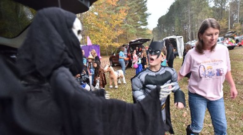 David Dakake, 12, reacts as Tina Watson (right) assists him during a special trunk-or-treat Wednesday night in Paulding County. (HYOSUB SHIN / HSHIN@AJC.COM)