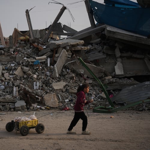 A girl carries bread as she walks past destruction left by Israeli air and ground operations in Gaza City Saturday, Nov. 29, 2025. (AP Photo/Abdel Kareem Hana)