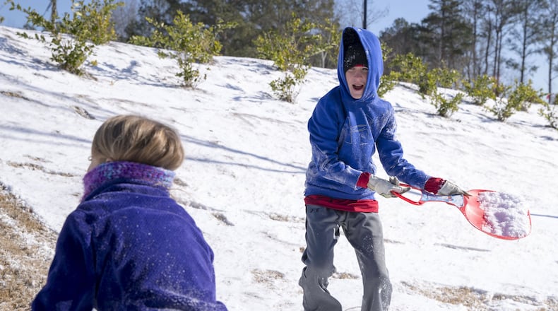 Andrew Marsden, 10, right, prepares to throw snow onto his sister, Molly Marsden, 8, as they play outside during Wednesday’s snow day in Alpharetta. ALYSSA POINTER/ALYSSA.POINTER@AJC.COM