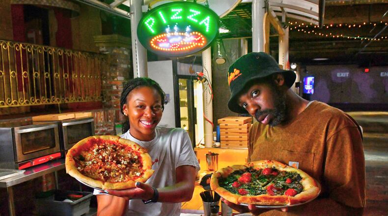 Dolo’s Pizza pop-up in Underground Atlanta, with owners Alyson Williams (left) and Yusef Walker showing off two of their pizzas. (CHRIS HUNT FOR THE ATLANTA JOURNAL-CONSTITUTION)