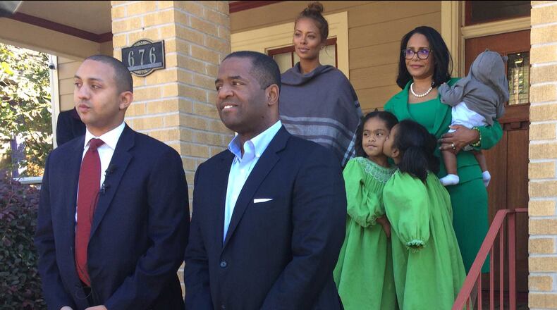 Michael Sterling, front left, and Ceasar Mitchell, front right, stand in front of Mitchell’s West End home with their families.