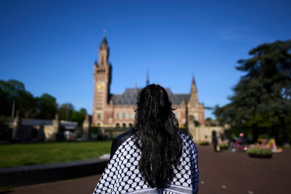 A woman wearing a keffieh stands in front of the International Court of Justice which opens hearings into a United Nations request for an advisory opinion on Israel's obligations to allow humanitarian assistance in Gaza and the West Bank, in The Hague, Netherlands, Monday, April 28, 2025. (AP Photo/Peter Dejong)