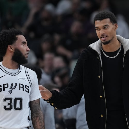 San Antonio Spurs forward Victor Wembanyama, right, talks with teamamte forward Julian Champagnie (30) during the first half of an NBA basketball game against the Sacramento Kings in San Antonio, Sunday, Nov. 16, 2025. (AP Photo/Eric Gay)