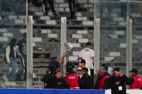 Security stewards confront fans after glass panels were broken and people invaded the field during a Copa Libertadores Group E soccer match against Brazil's Fortaleza at Monumental Stadium in Santiago, Chile, Thursday, April 10, 2025. (AP Photo/Esteban Felix)