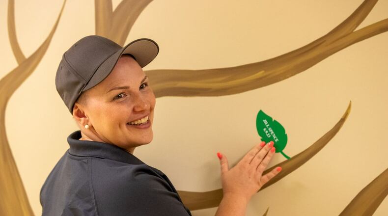 Forsyth County 911 Center Operations Manager Jill Spence places a leaf on the county's Tree of Life for saving the life of a man who experienced sudden cardiac arrest. (Courtesy of Forsyth County)