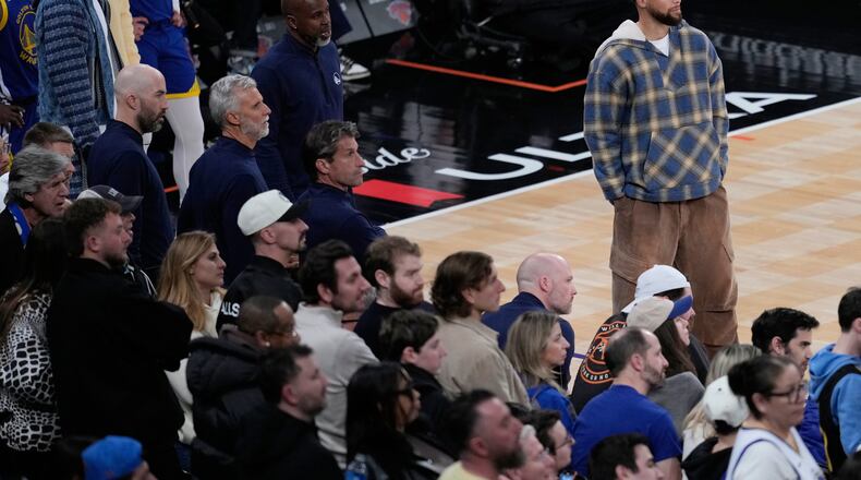 Golden State Warriors' Stephen Curry, top right, watches the end of an NBA basketball game against the New York Knicks Sunday, March 15, 2026, in New York. (AP Photo/Seth Wenig)