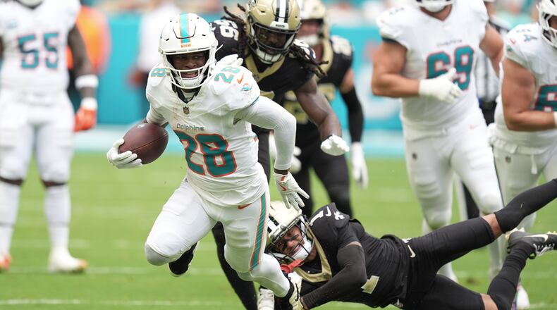 FILE - Miami Dolphins running back De'Von Achane (28) escapes a tackle by New Orleans Saints cornerback Alontae Taylor (1) during the first half of an NFL football game, Nov. 30, 2025, in Miami Gardens, Fla. (AP Photo/Rebecca Blackwell, File)