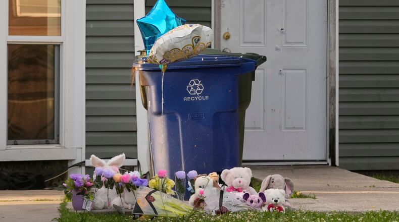A makeshift memorial is growing on the front lawn of a home as the door in the background shows bullet holes and evidence markers where children were killed during a mass shooting the day before in Shreveport, La., Monday, April 20, 2026. (AP Photo/Gerald Herbert)